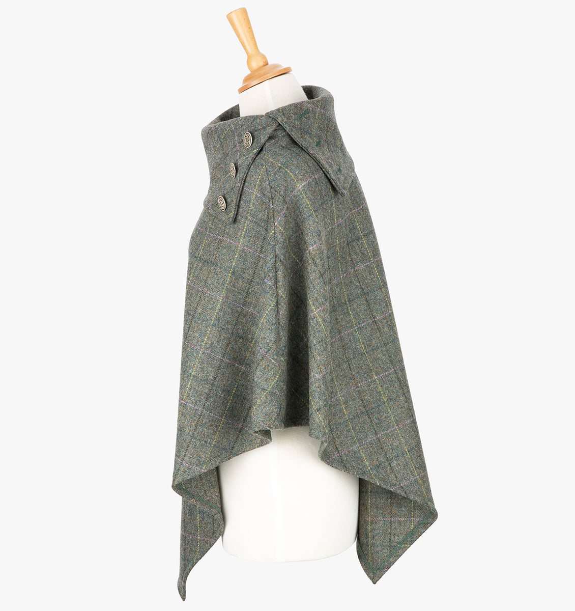 Side view the poncho in grey check. It drops over the head and drapes gently over the shoulders. It comes mid-way down the arms and finishes at a point at the front. The colour is grey check with a black, yellow, pink and blue overcheck. It has a contrasting folded collar with 3 Celtic buttons in silver.